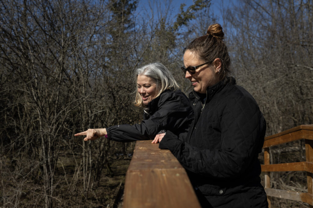 Karen van der Zalm and another woman standing on a woodne bridge