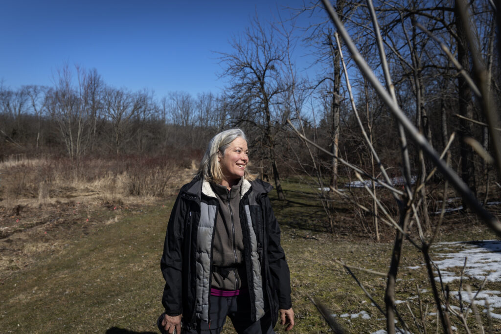 Karen van der Zalm standing among the trees in a grassy opening