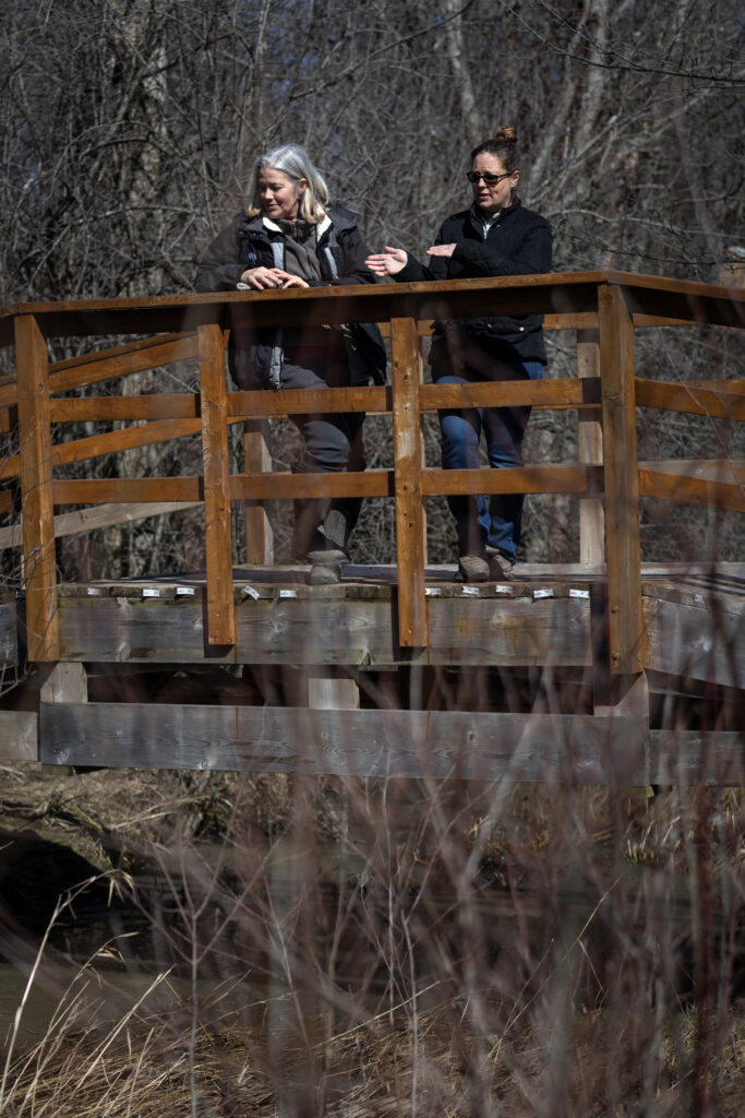Karen van der Zalm and another woman standing on a wooden bridge