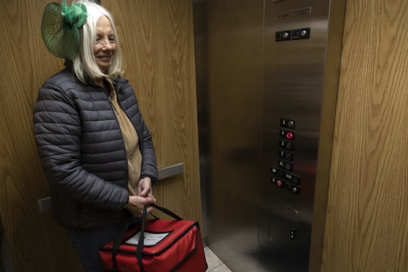 A worker from Meals on Wheels waits in an elevator.