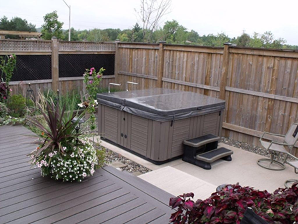 Spa in an outdoor oasis with seating, privacy fencing and garden